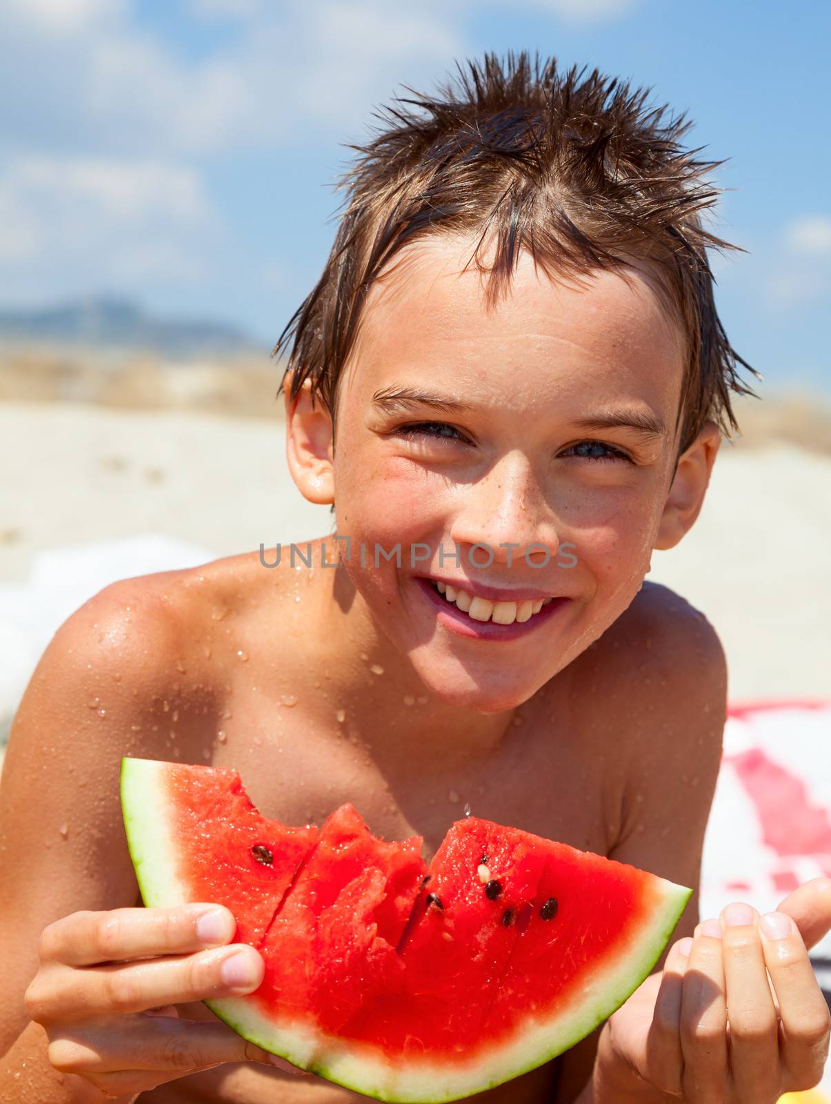 Boy eating melon on a beach by naumoid