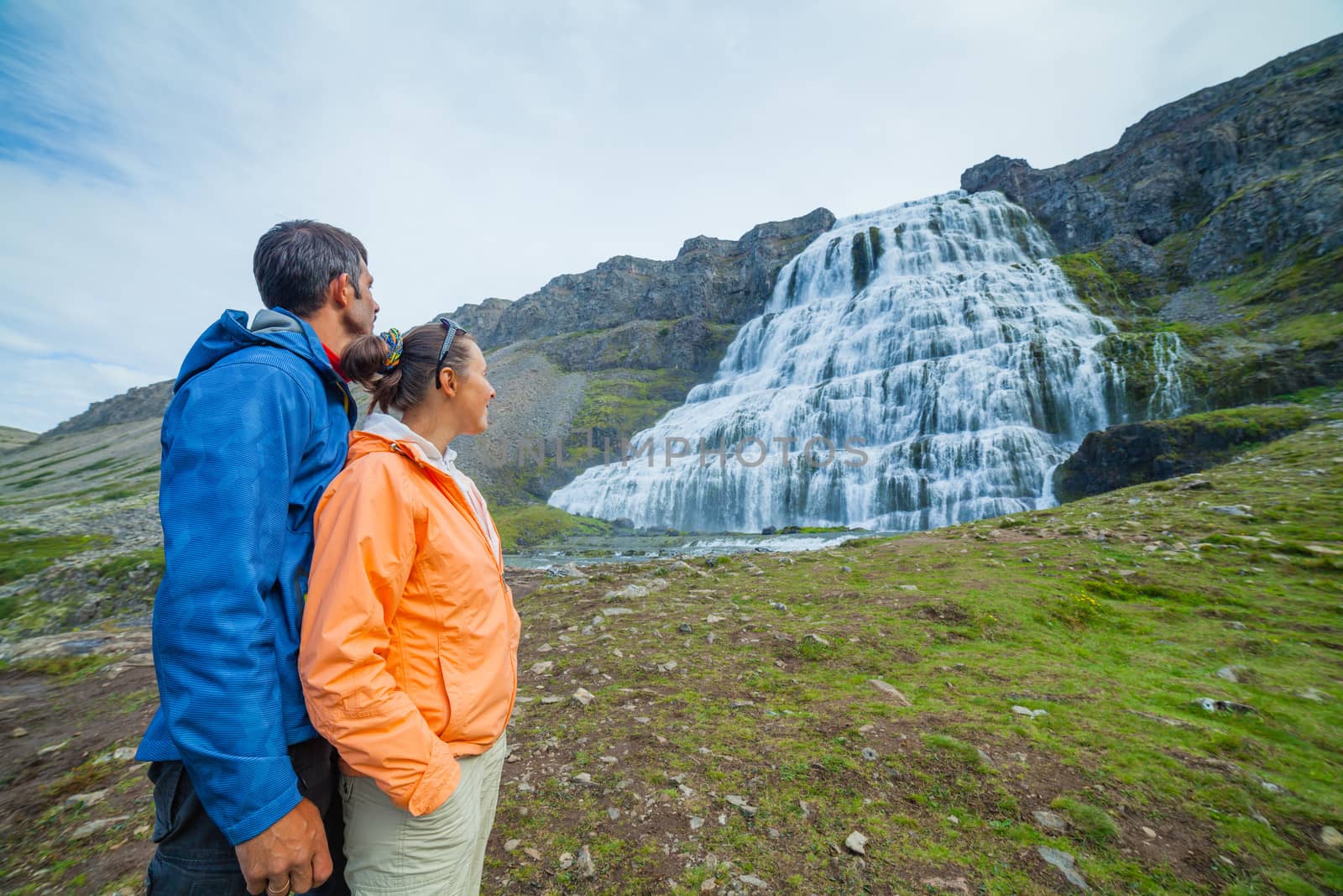 Couple of tourists near Dynjandi is the most famous and beautiful waterfall of the West Fjords in Iceland.