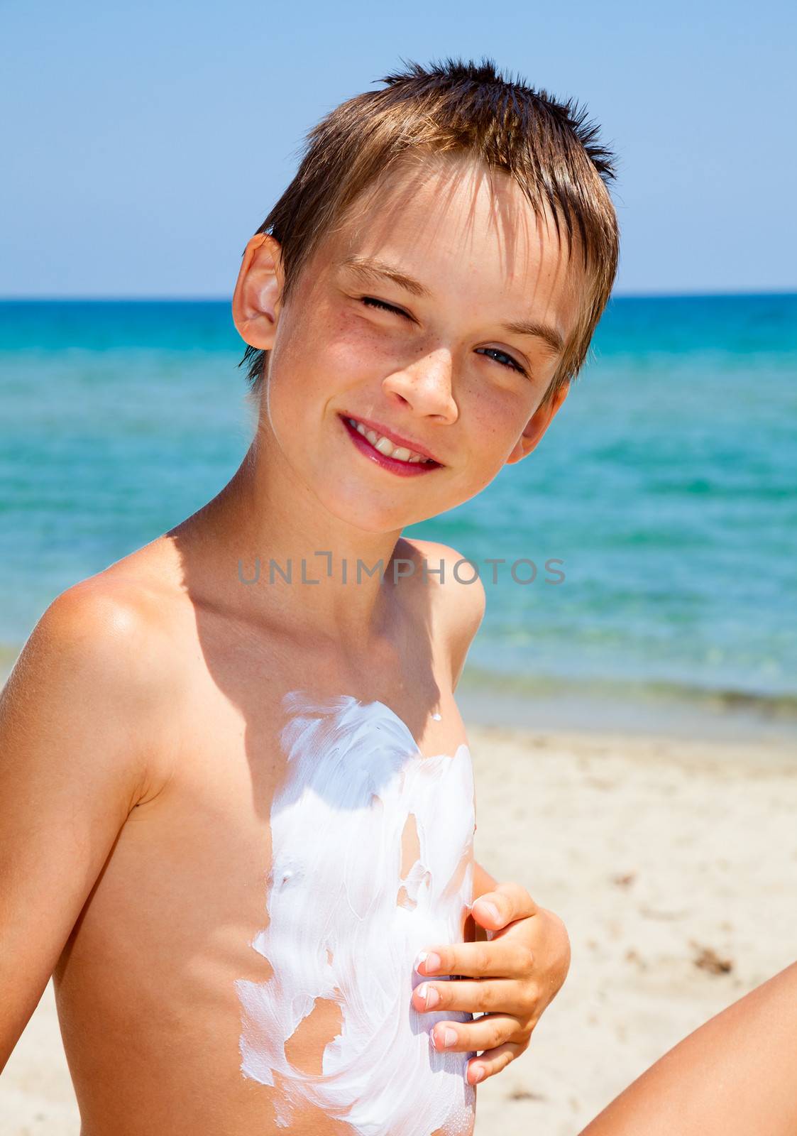 Boy applying sunscreen by naumoid
