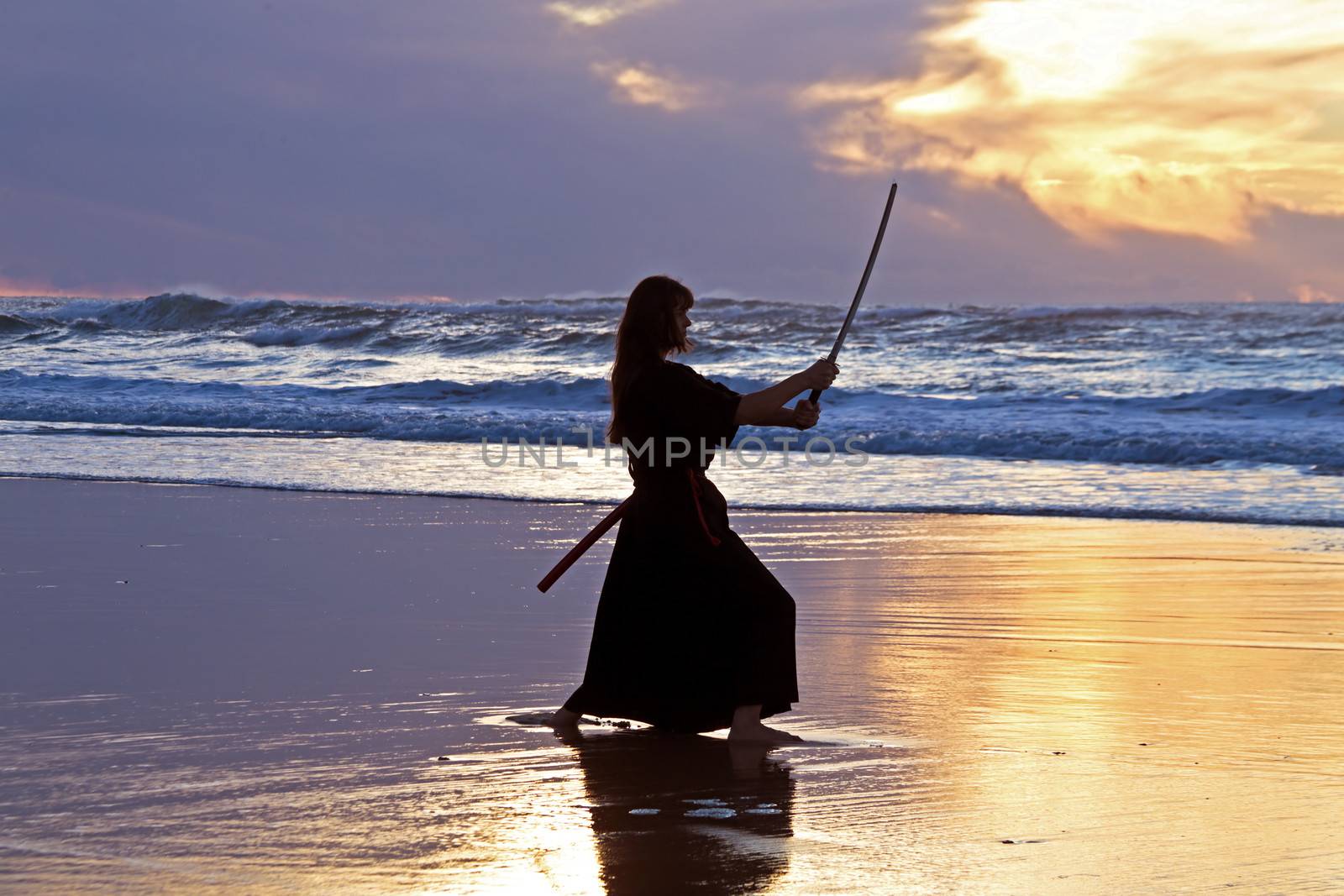 Young samurai women with Japanese sword(Katana) at sunset on the beach