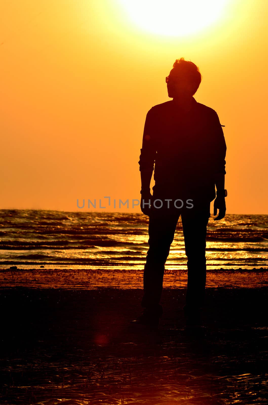 Silhouette man on beach with sunset sky background by pixbox77