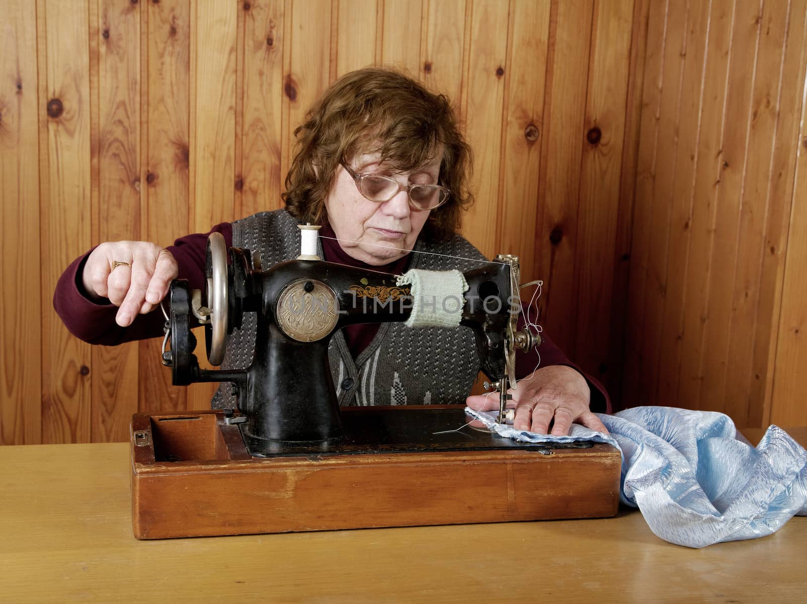 The old woman sews on the sewing machine