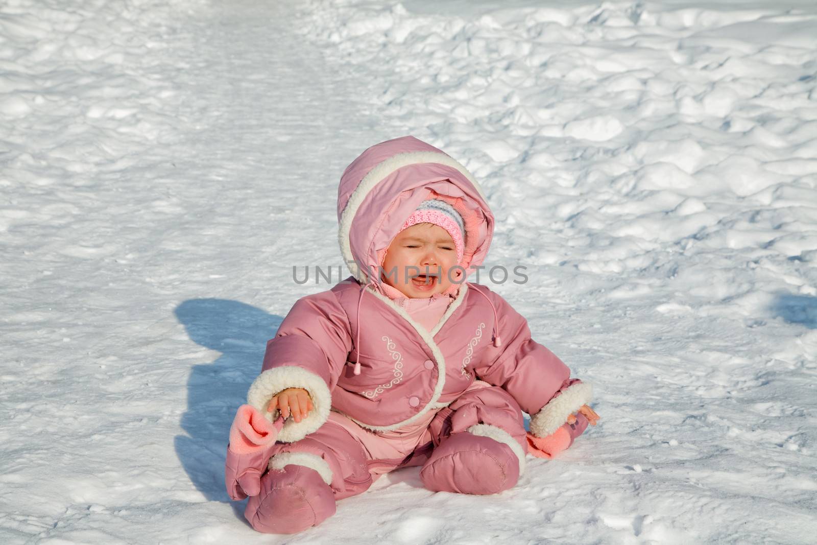 The little girl cries sitting on snow