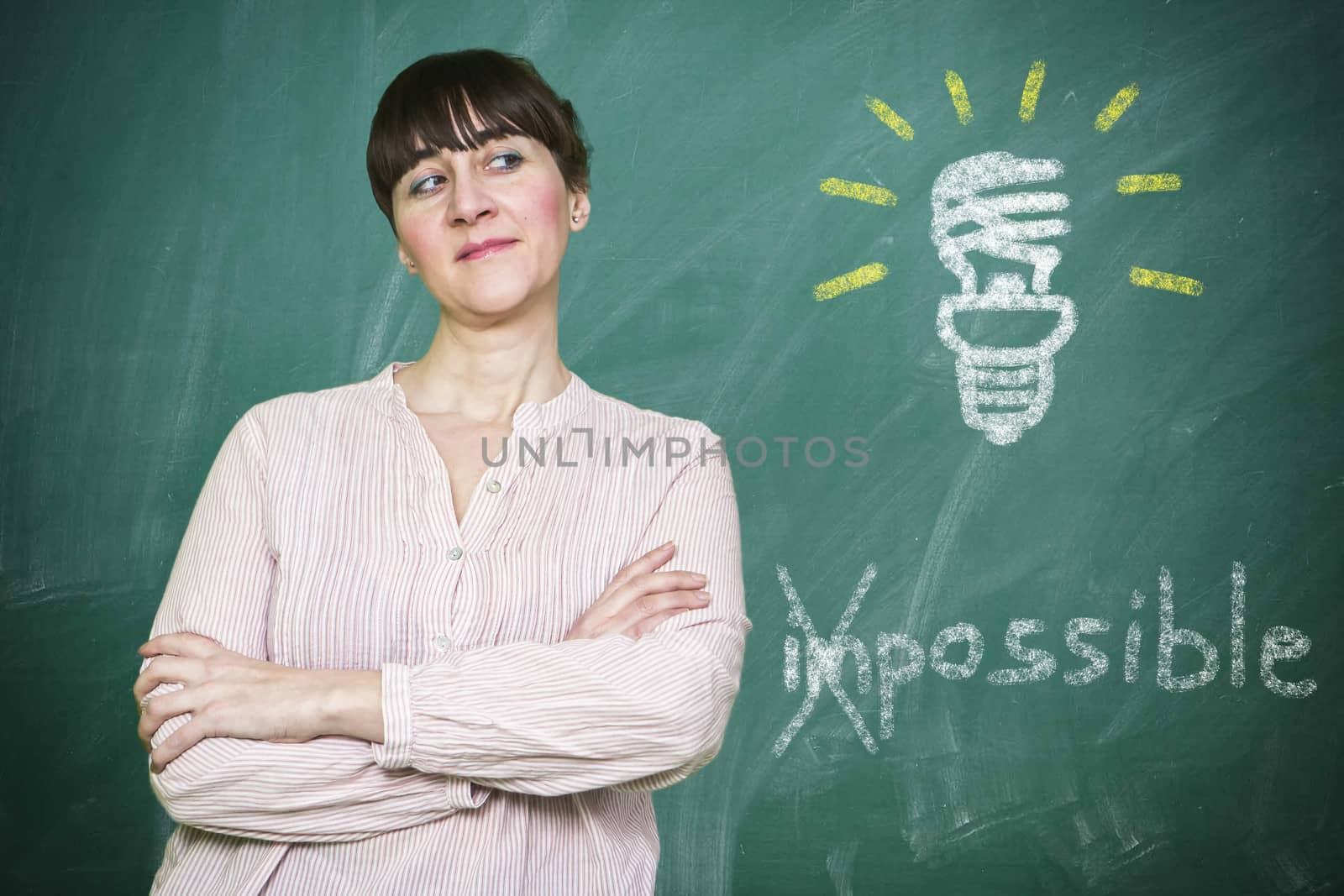 Woman smiles writes on a blackboard the concept of saving energy is possible