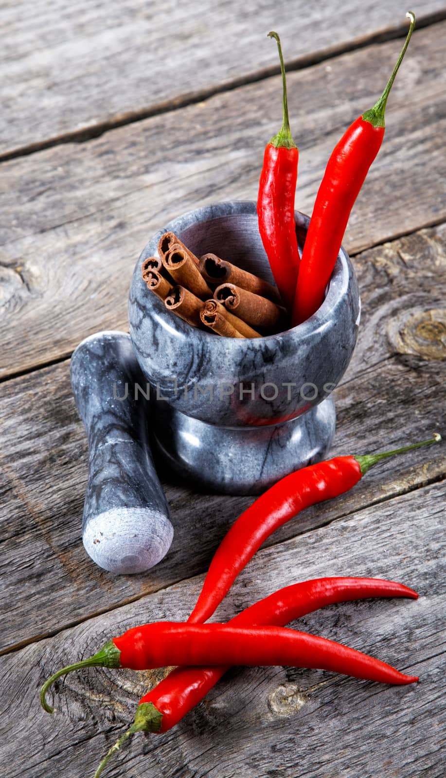 Mortar with cinnamon and chilli pepper on an old table