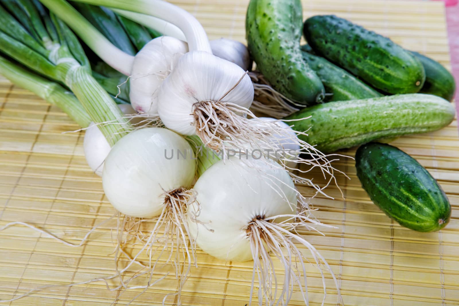 Still-life with onions garlic and green cucumbers on a table