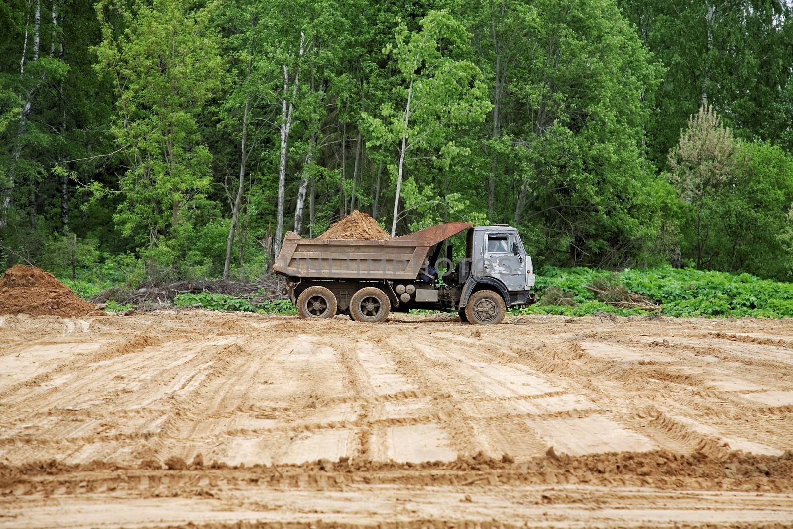 dump-body truck unloads a ground on the land