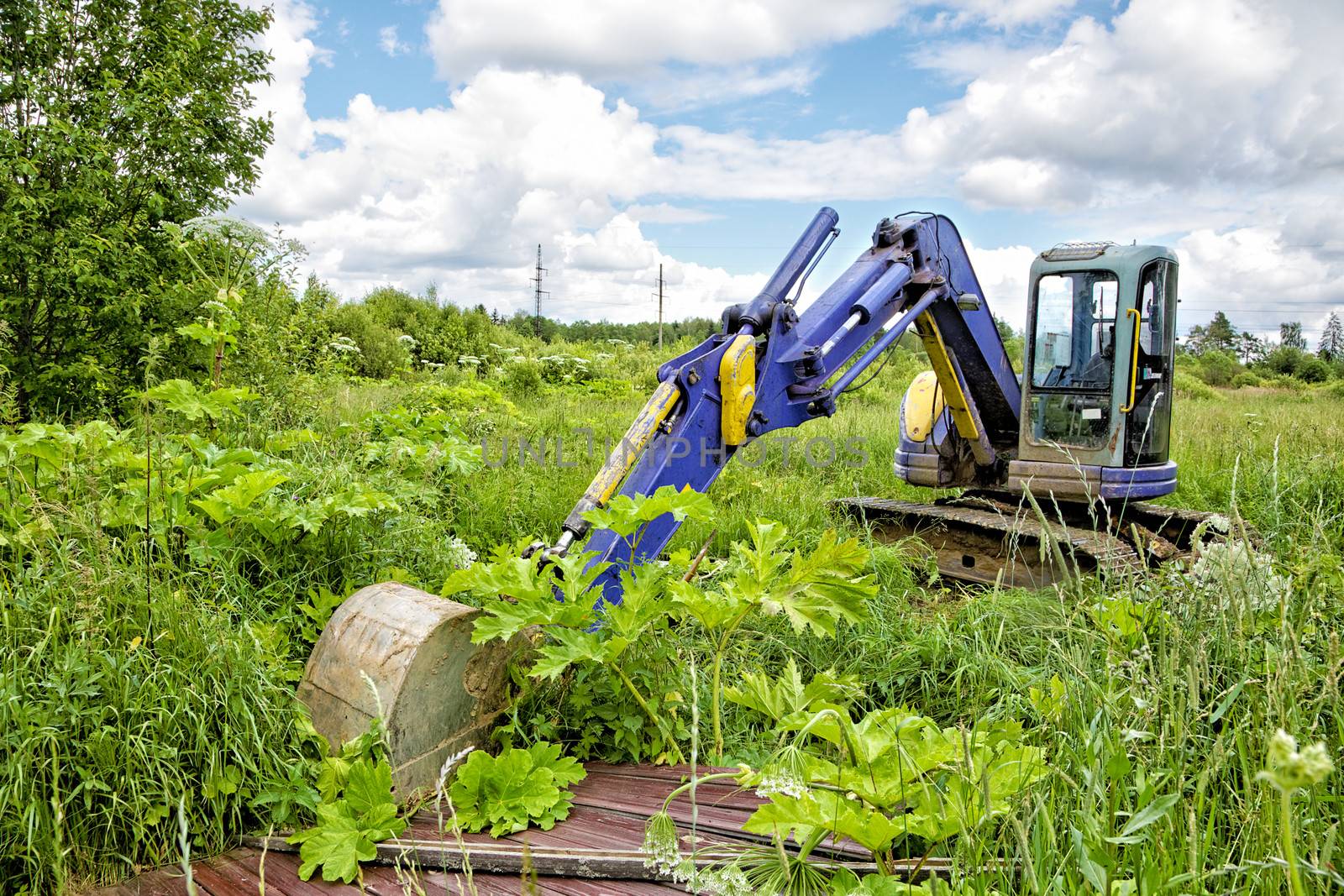 Caterpillar dredge in the field among a grass