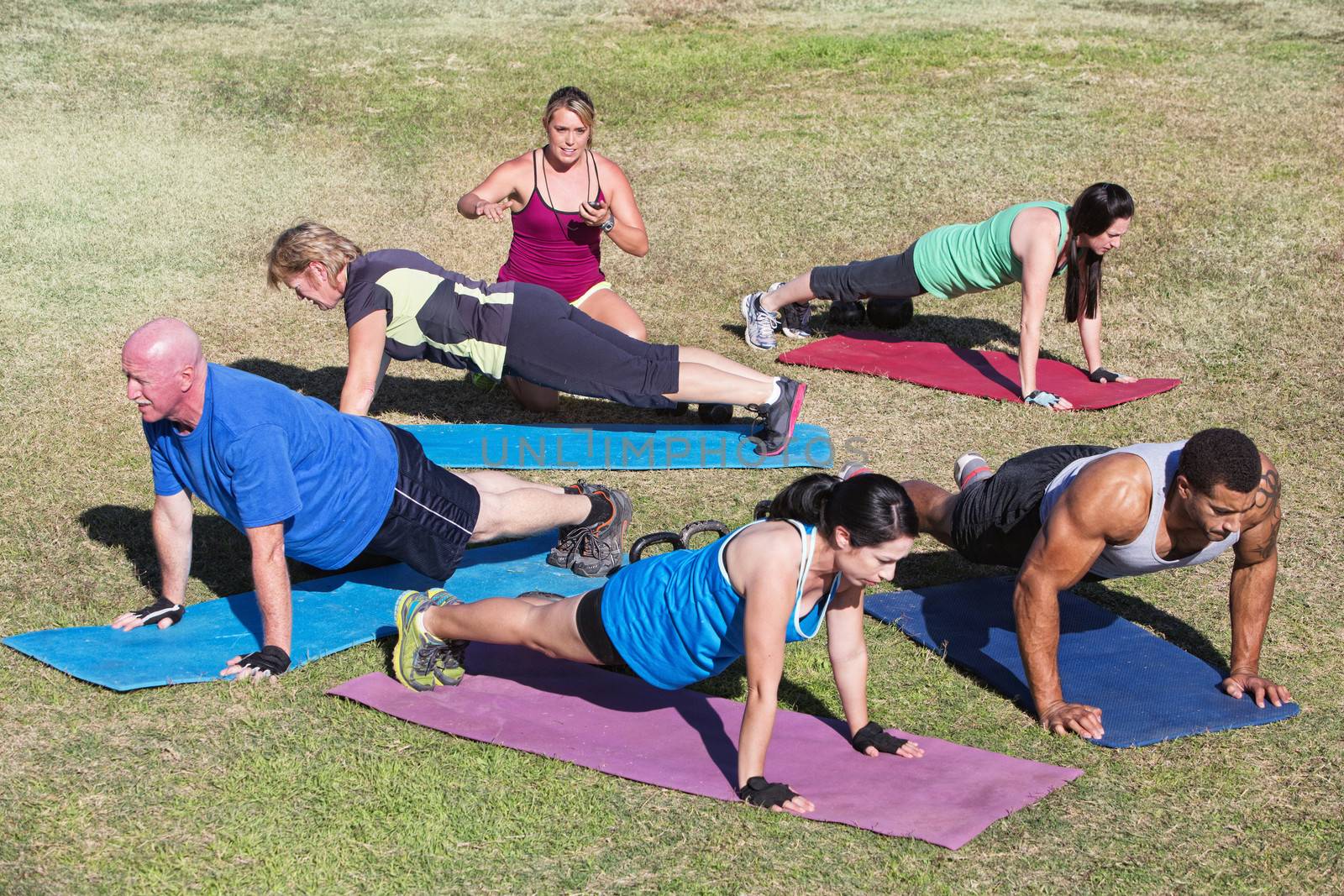 Mixed group of people doing push ups outdoors