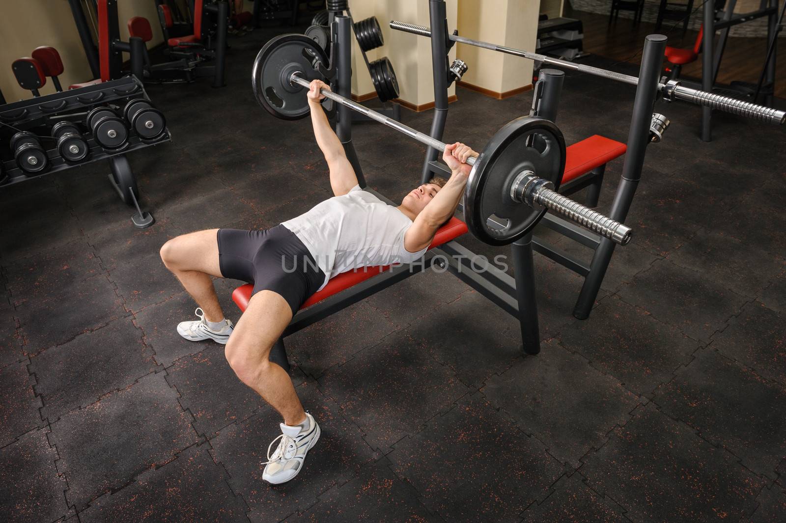 handsome young man doing bench press workout in gym