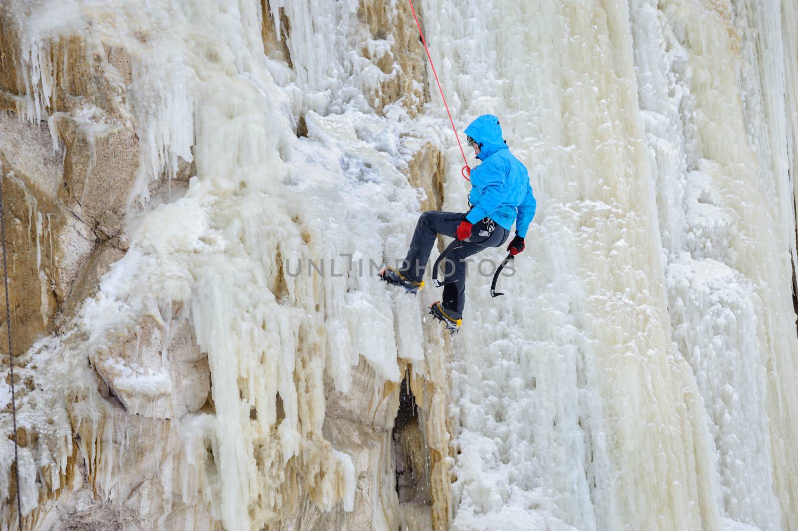 Young man climbing the ice using ice axe, motion blur