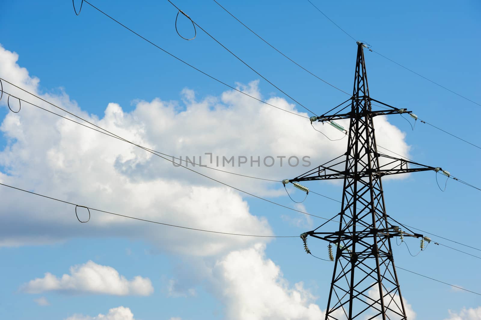 High voltage overhead power line and blue sky behimd