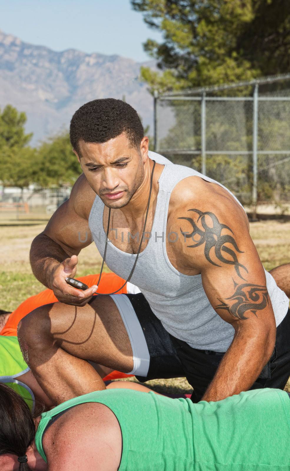 Athletic trainer with tattoo and outdoor fitness class