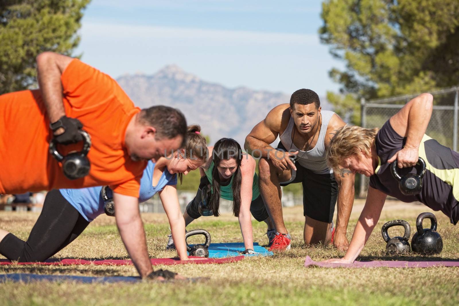 Fitness instructor with people exercising in outdoor bootcamp