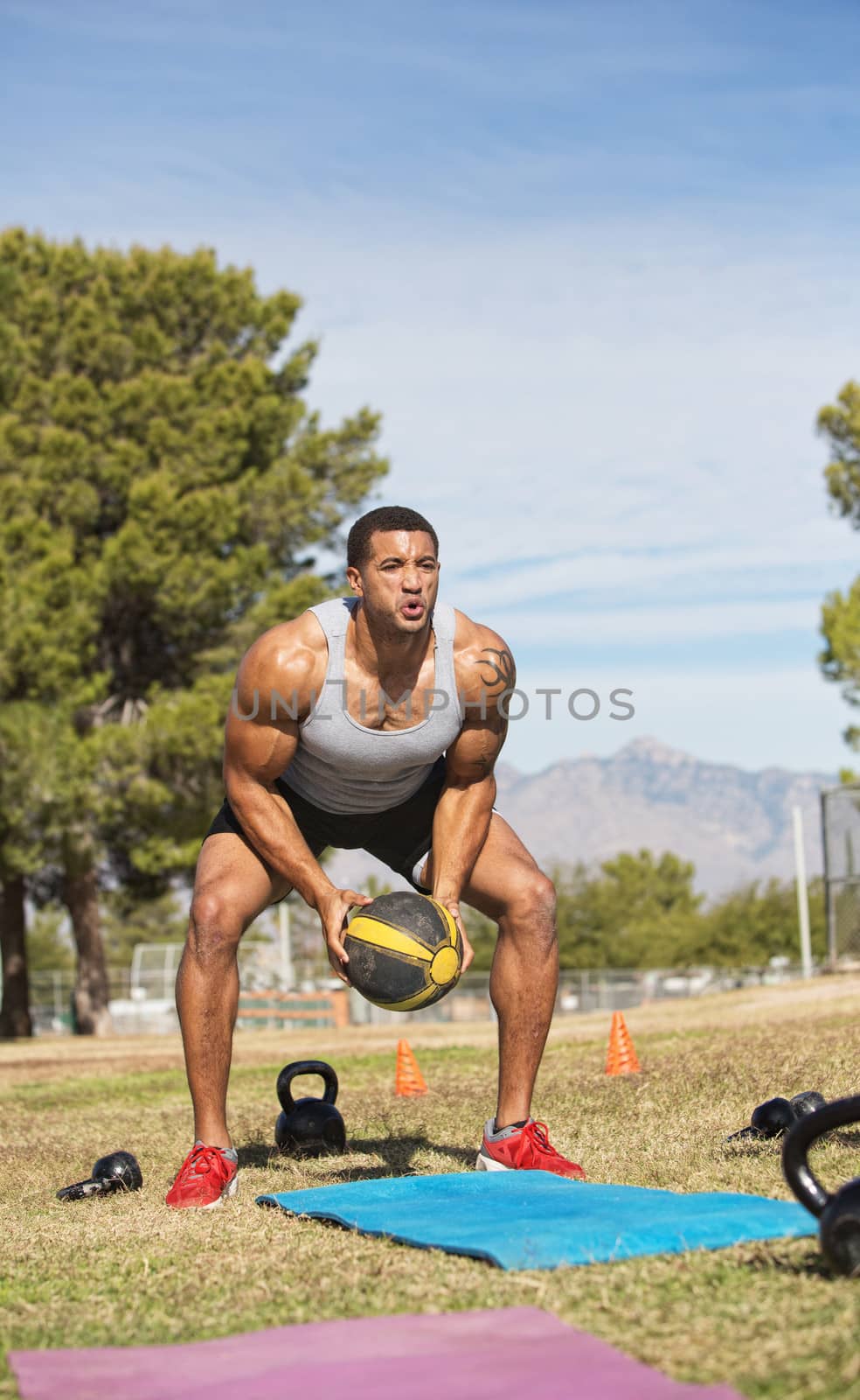 Single man squatting and lifting medicine ball