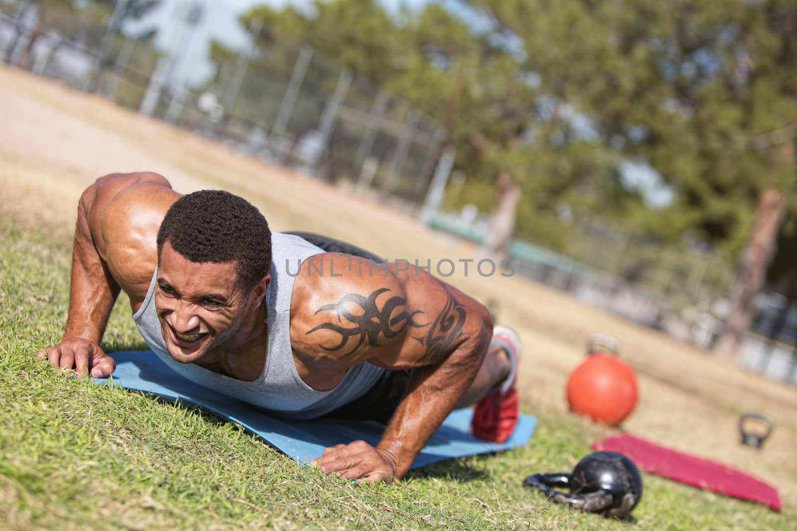 Strong man with tattoo doing push ups outdoors