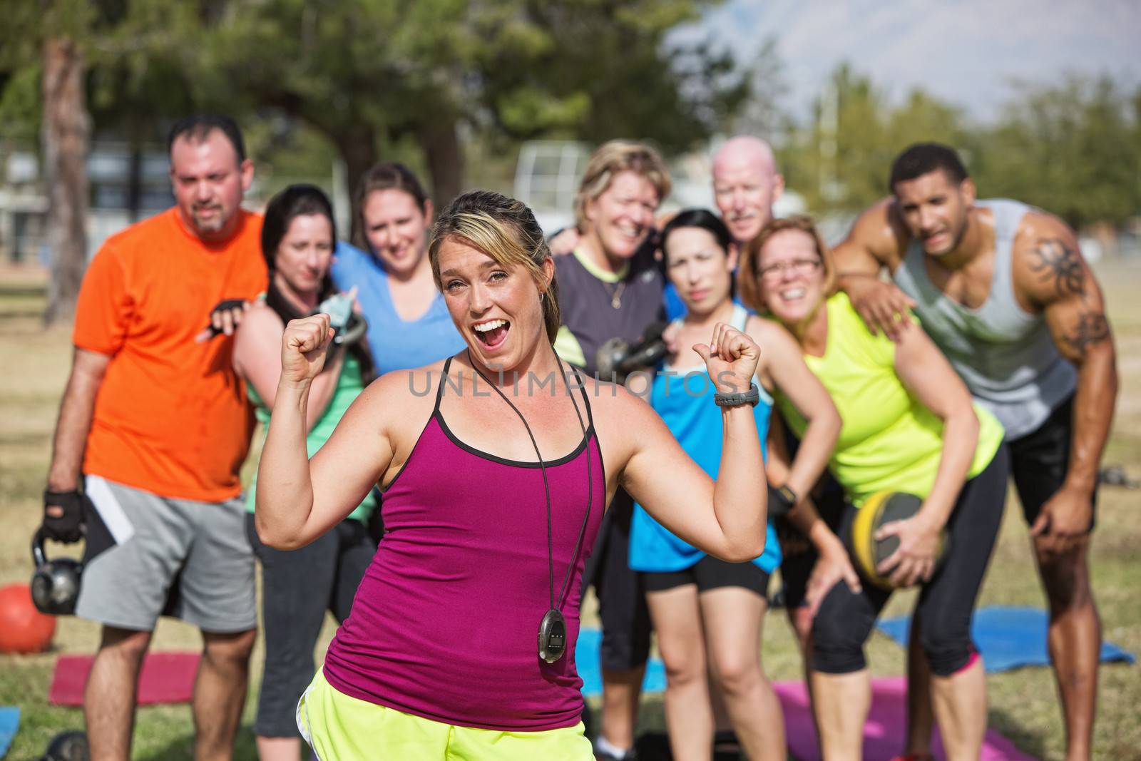 Enthusiastic  bootcamp fitness instructor with group outdoors