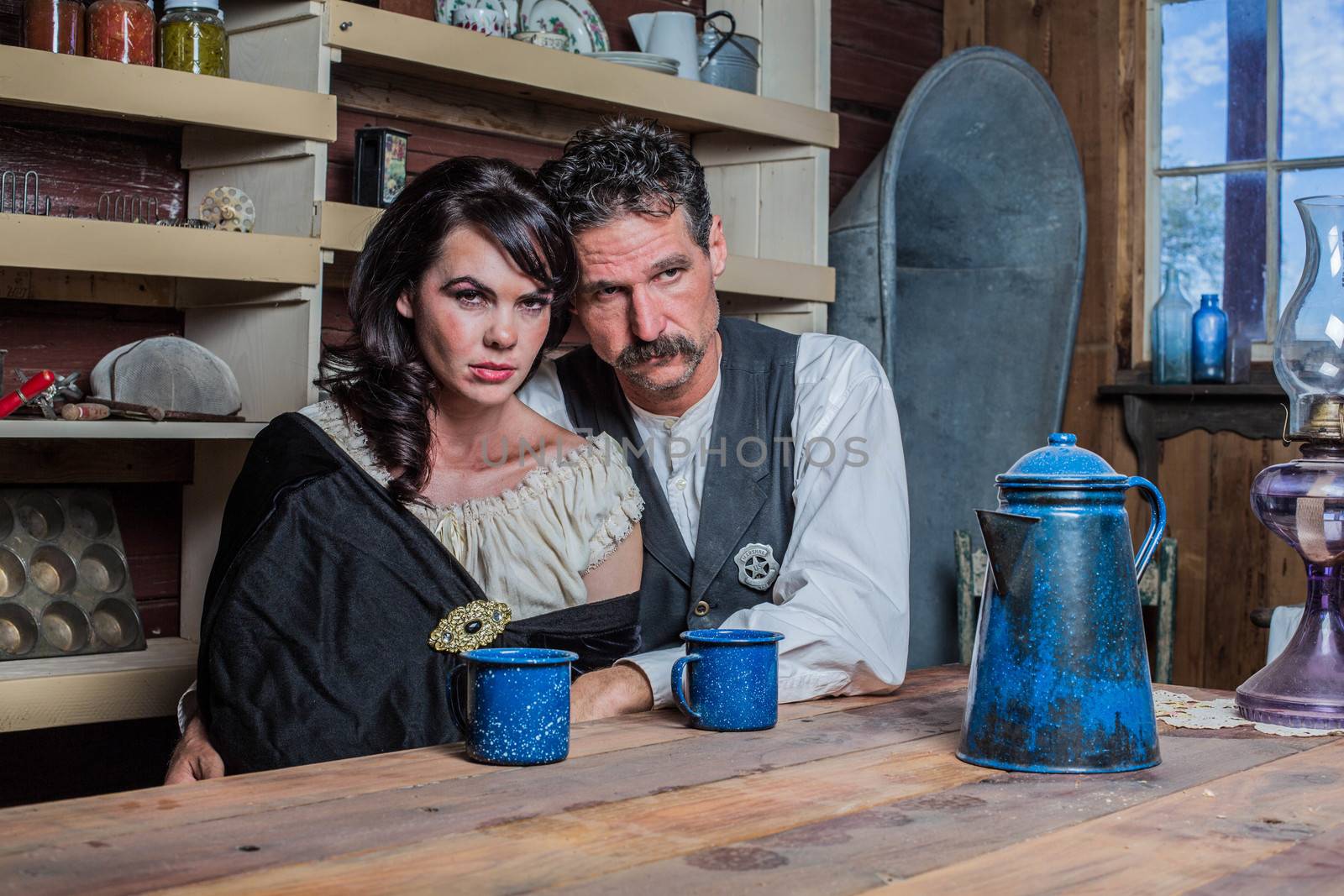 Serious looking western sheriff and woman pose inside of a house