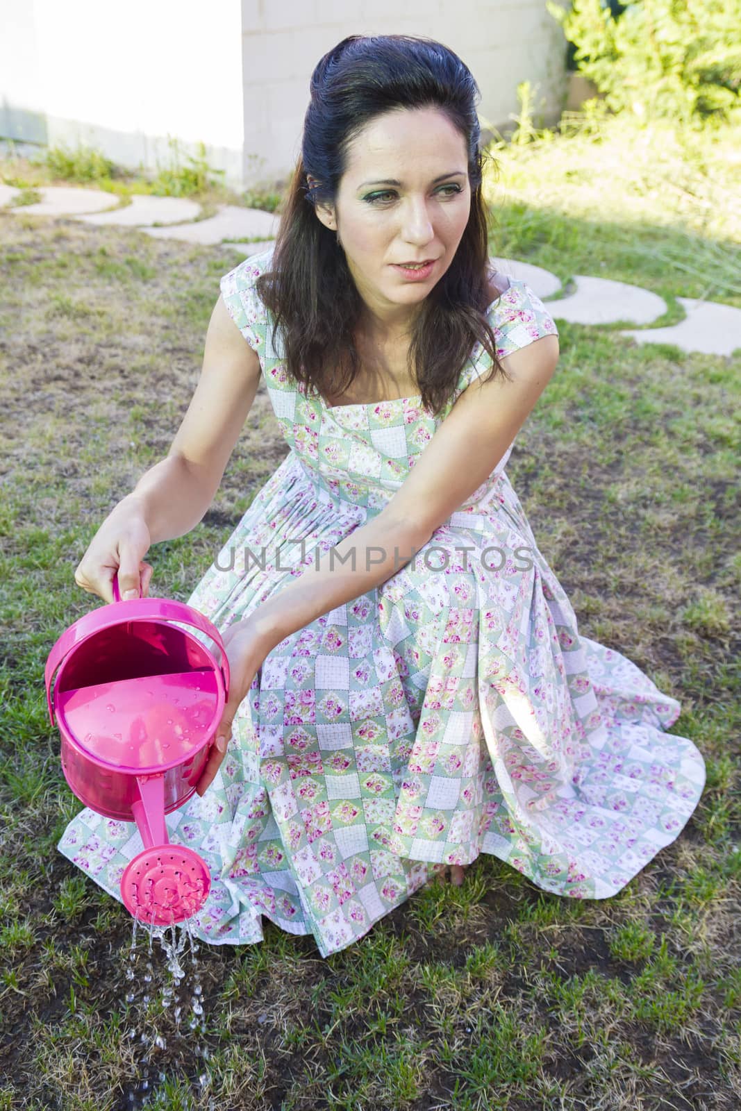 Woman watering green garden. Mature girl gardening in her backyard. spring season, rural scene