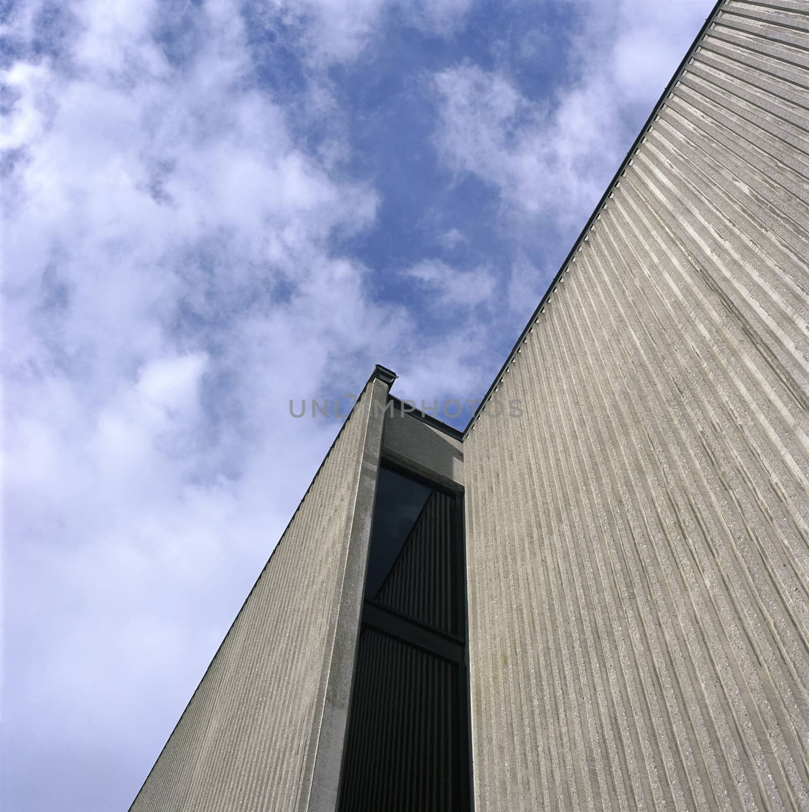 Large, modern concrete building and cloudy sky