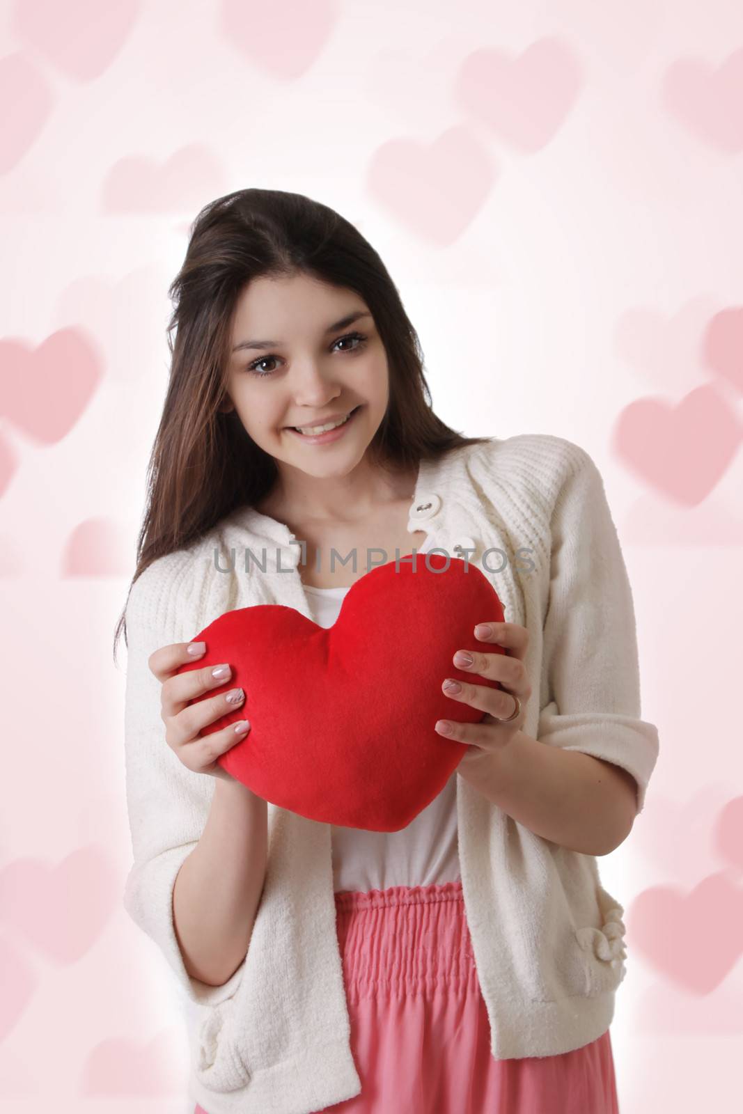Young girl with plush red heart on heart-shaped pink bokeh background