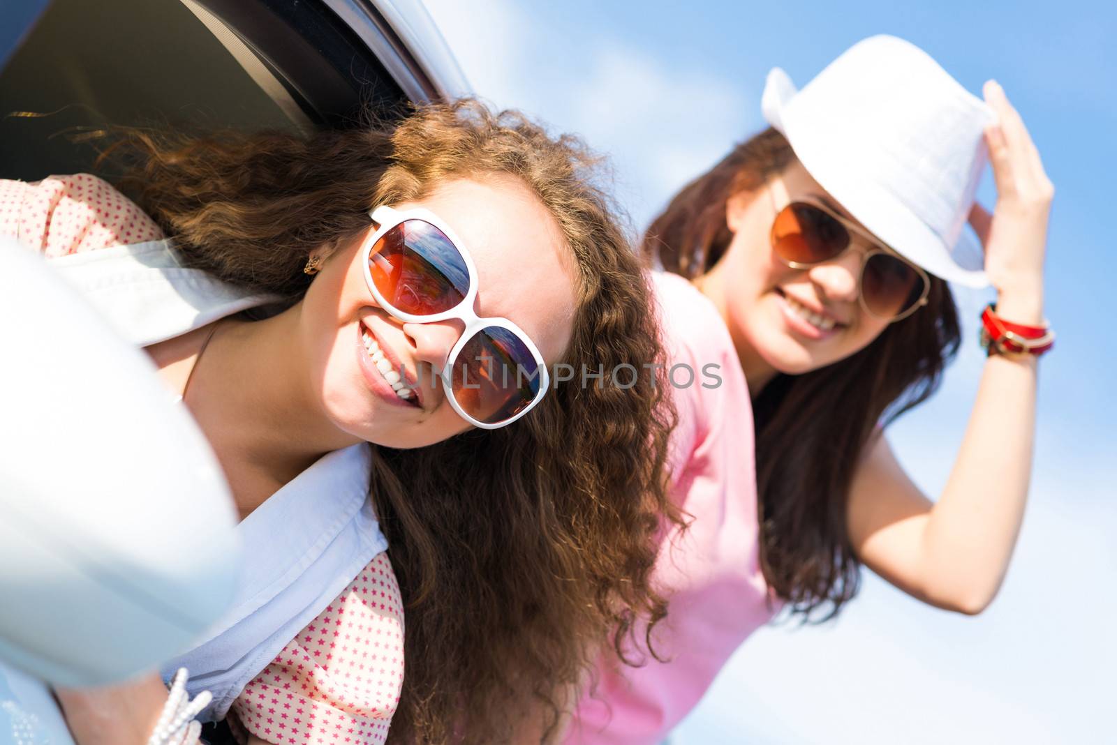 young attractive woman in sunglasses got out of the car window and laugh