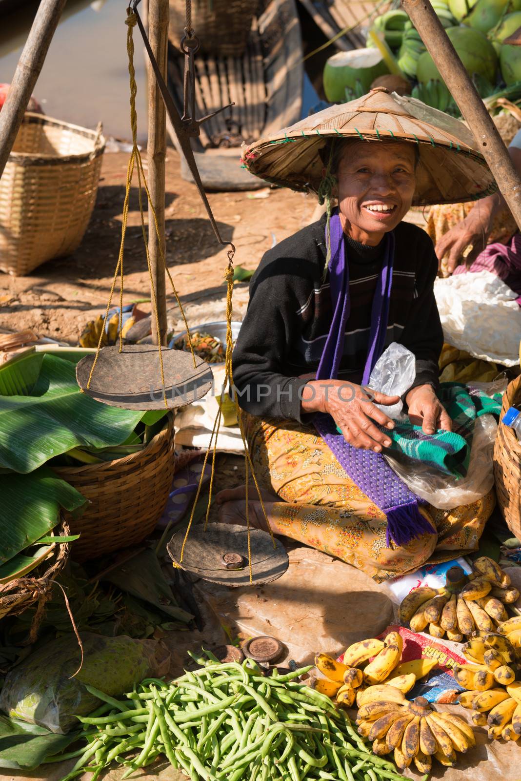 INLE LAKE, MYANMAR (BURMA) - 07 JAN 2014: Local Burmese Intha woman sell vegetable on a traditional open market. Local markets serves most common shopping needs Inle Lake people.