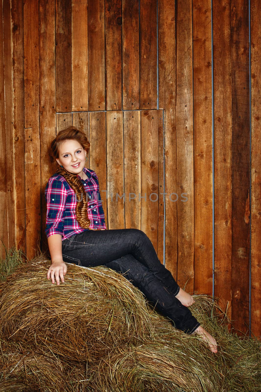 Cute little girl with a plait in a  lumberjack shirt in a rustic barn