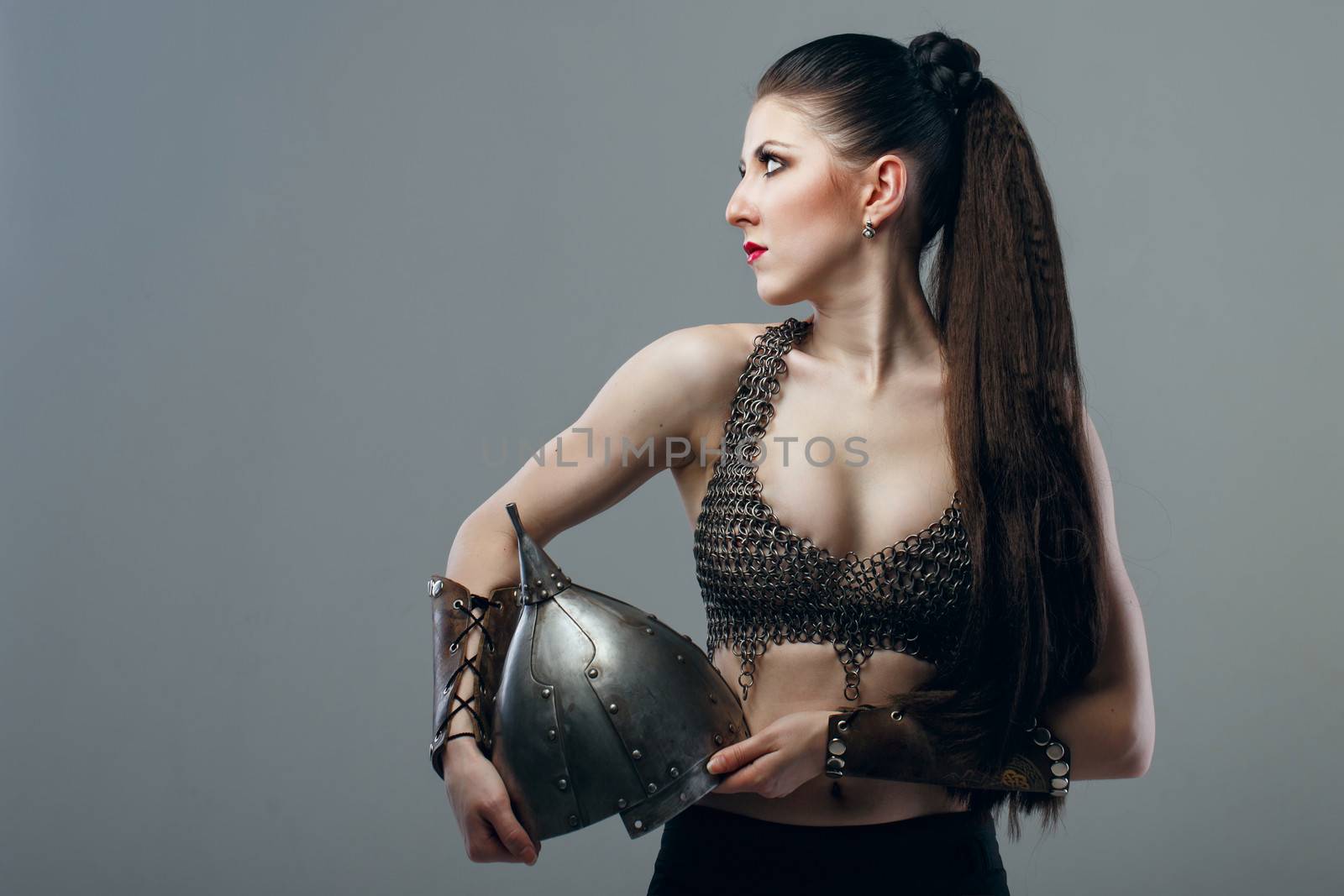 Attractive young girl warrior in chain mail holding helmet