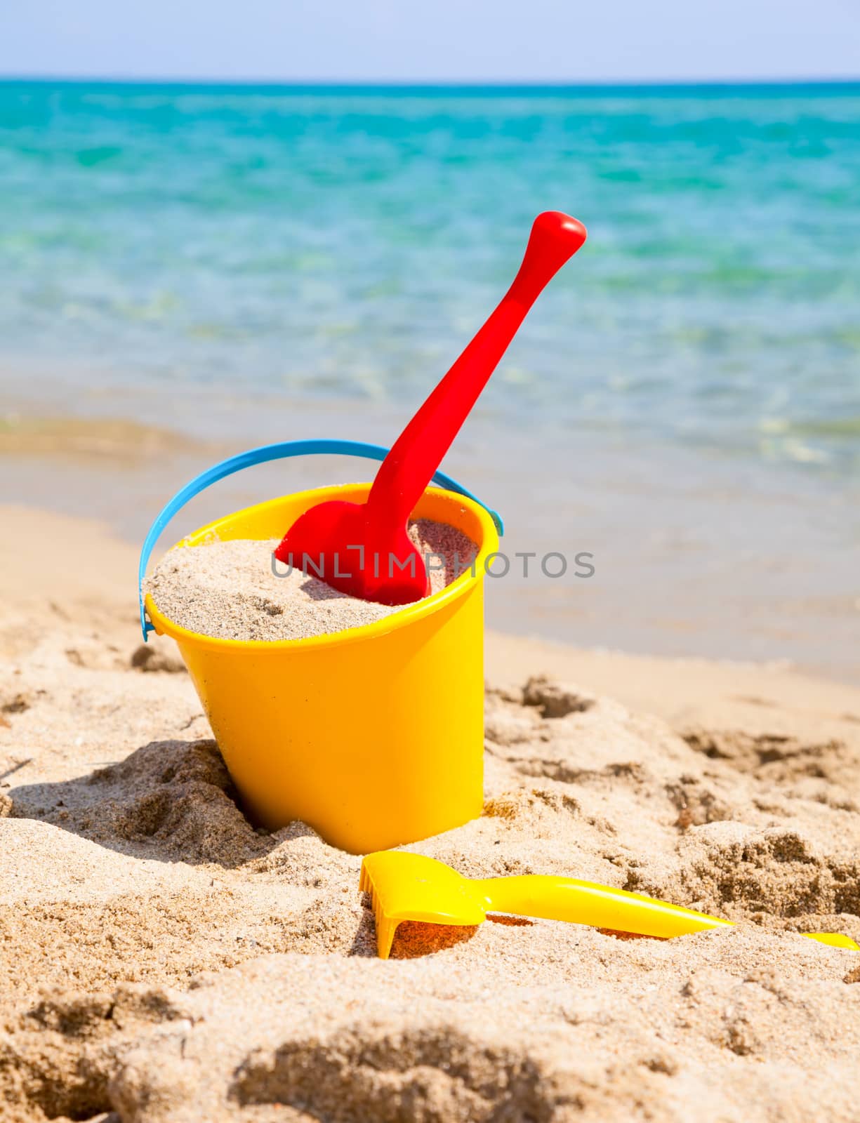 Yellow sand pail and shovel on a beach