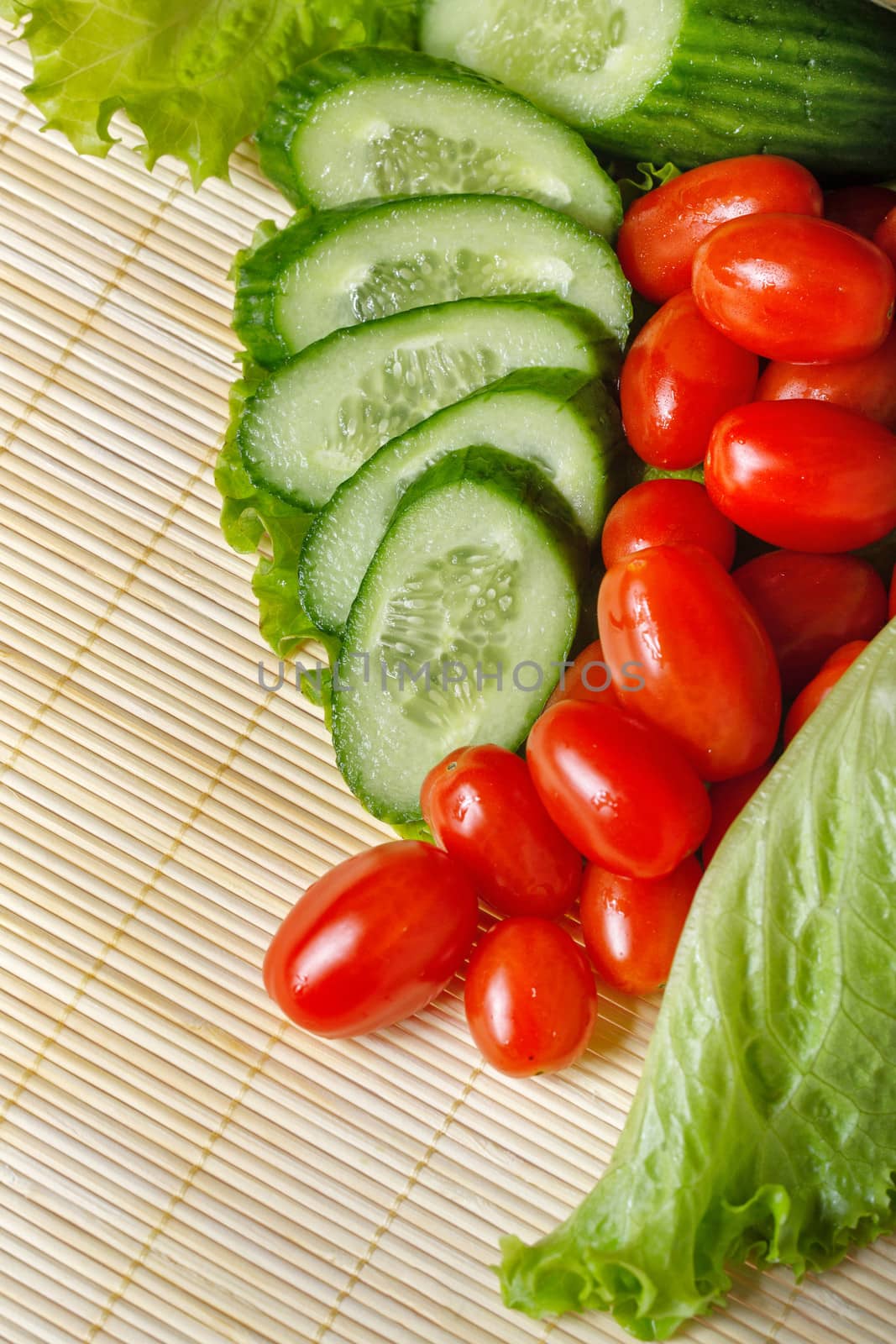 Ripe cherry tomatoes, cucumbers and lettuce closeup shot