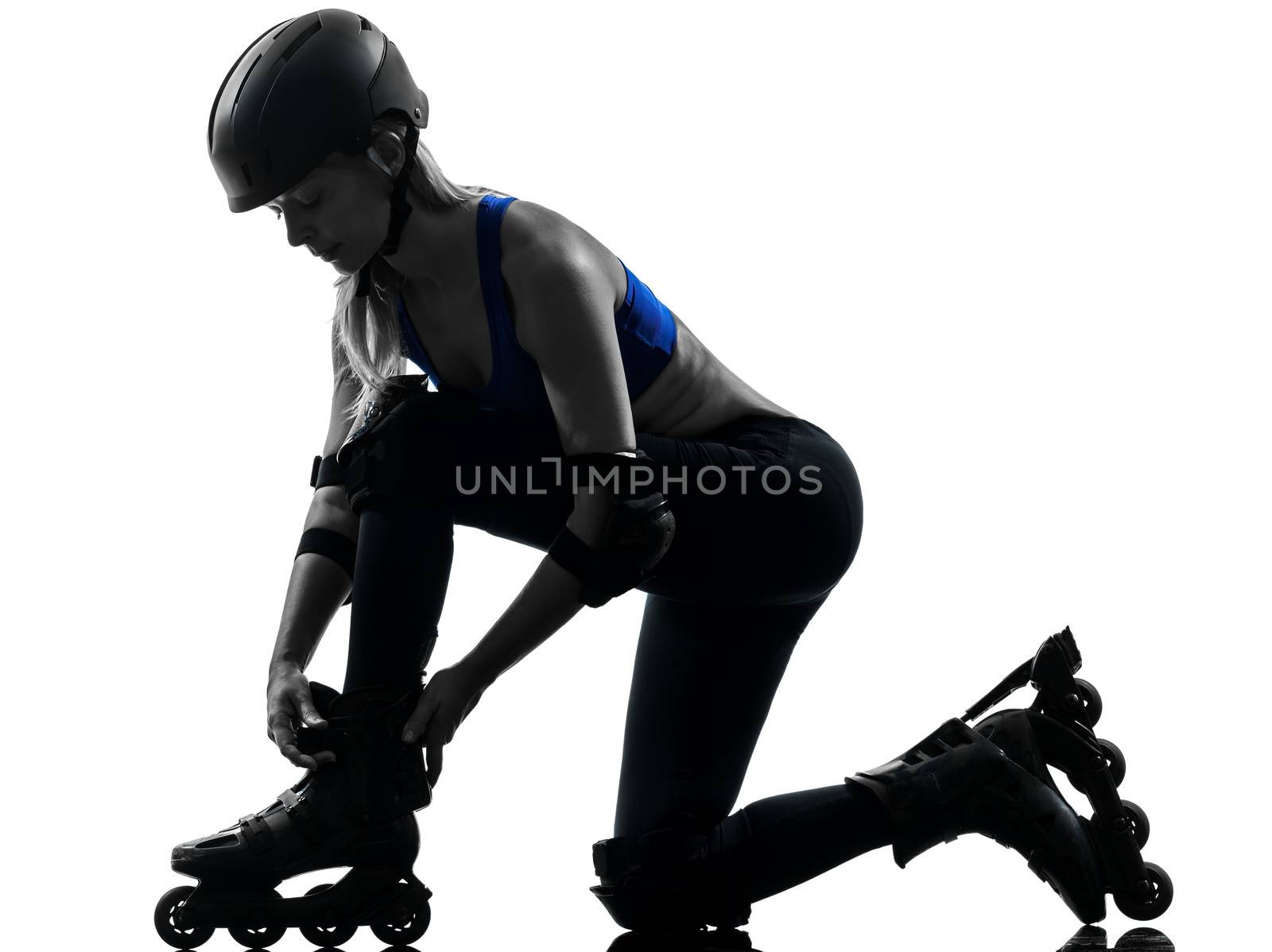 one caucasian woman tying roller skates silhouette studio isolated on white background