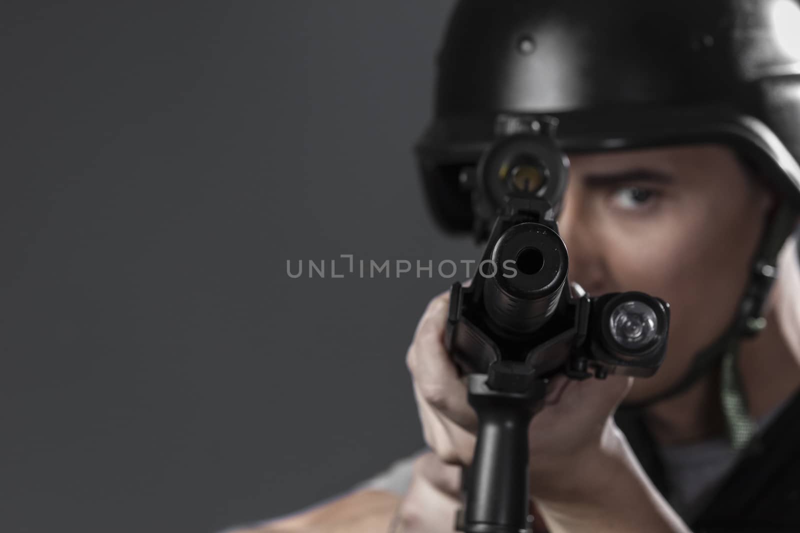Gunfire, paintball sport player wearing protective helmet aiming pistol ,black armor and machine gun