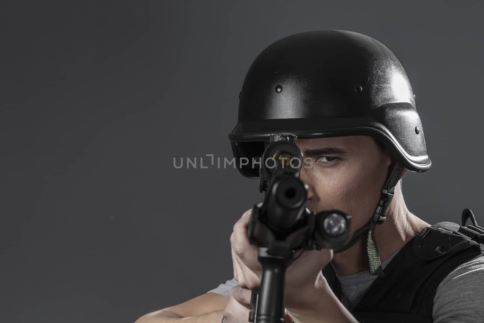Assault, paintball sport player wearing protective helmet aiming pistol ,black armor and machine gun