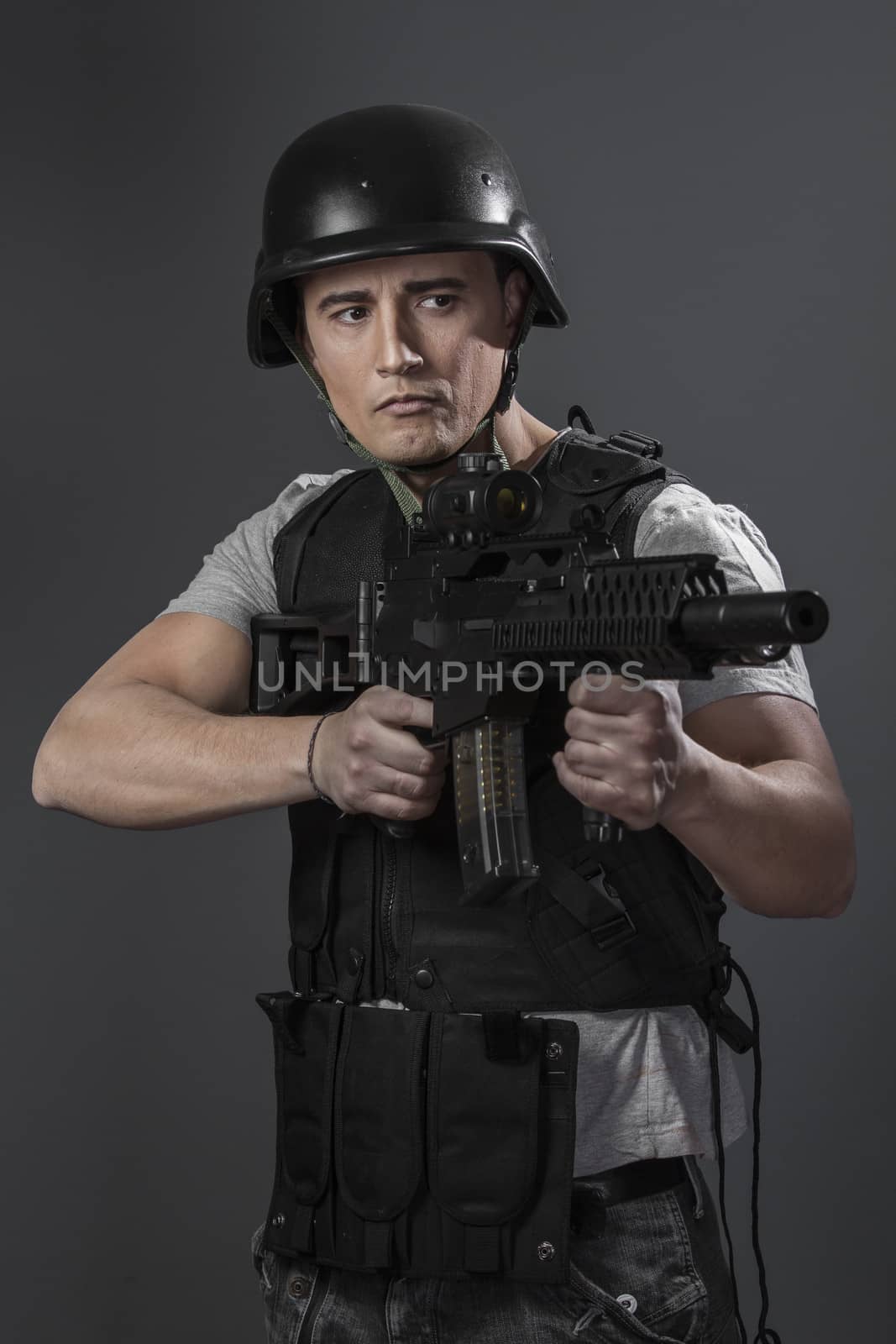 Soldier, paintball sport player wearing protective helmet aiming pistol ,black armor and machine gun