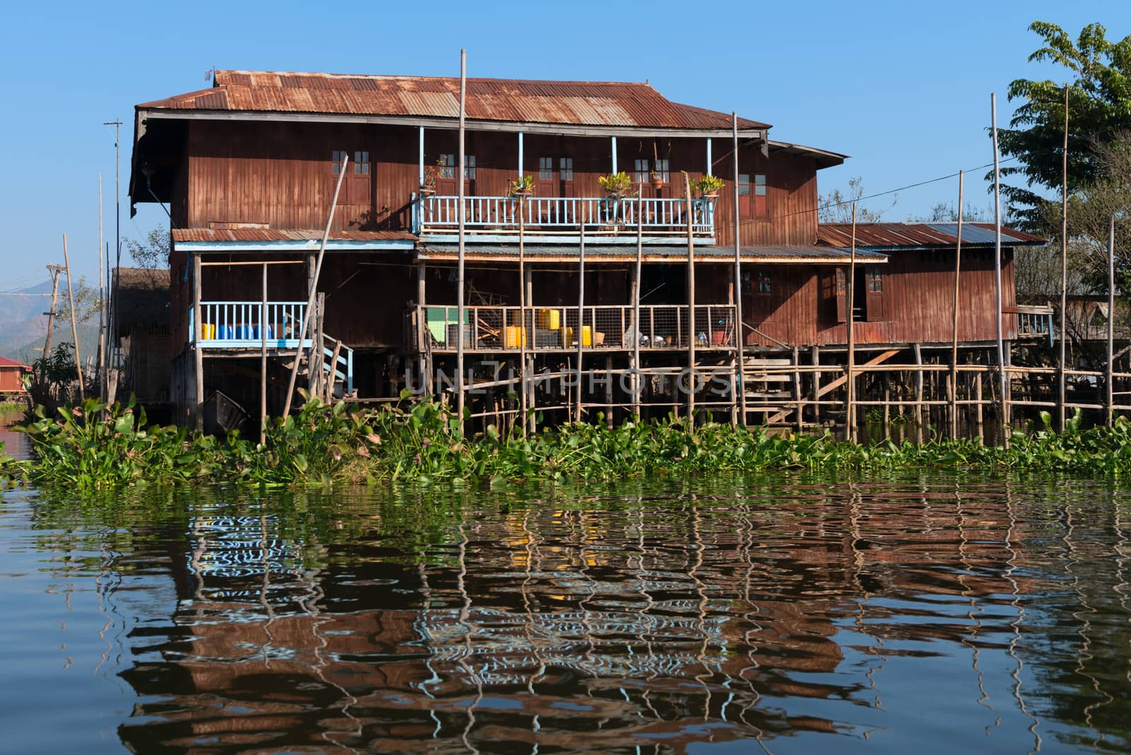 Traditional stilts house in water under blue sky by iryna_rasko