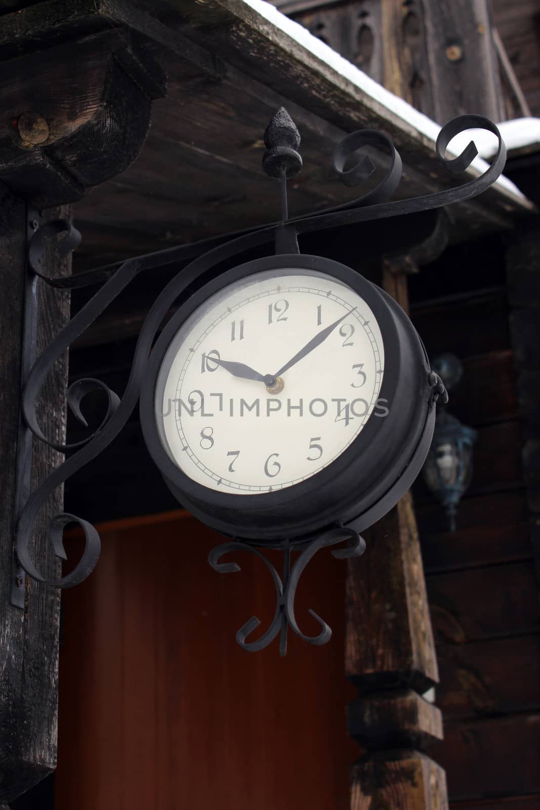 ancient clock hanging near the wooden building by alexmak
