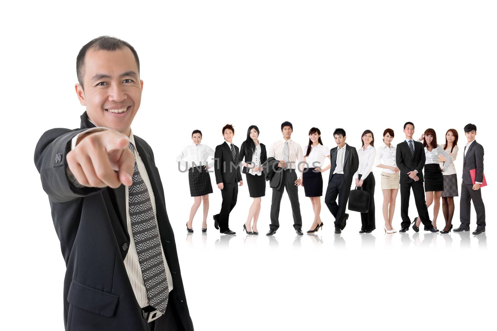 Smiling businessman of Asian point at you and standing in front of his team on studio white background.