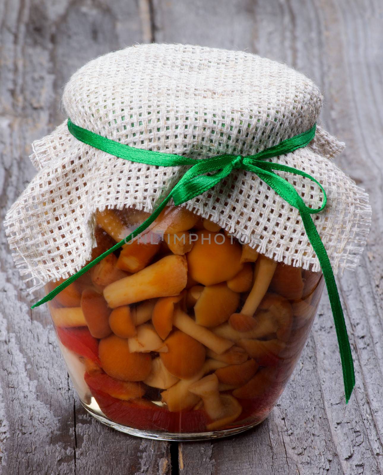 Delicious Marinated Forest Mushrooms in Glass Jar isolated on Rustic Wooden background