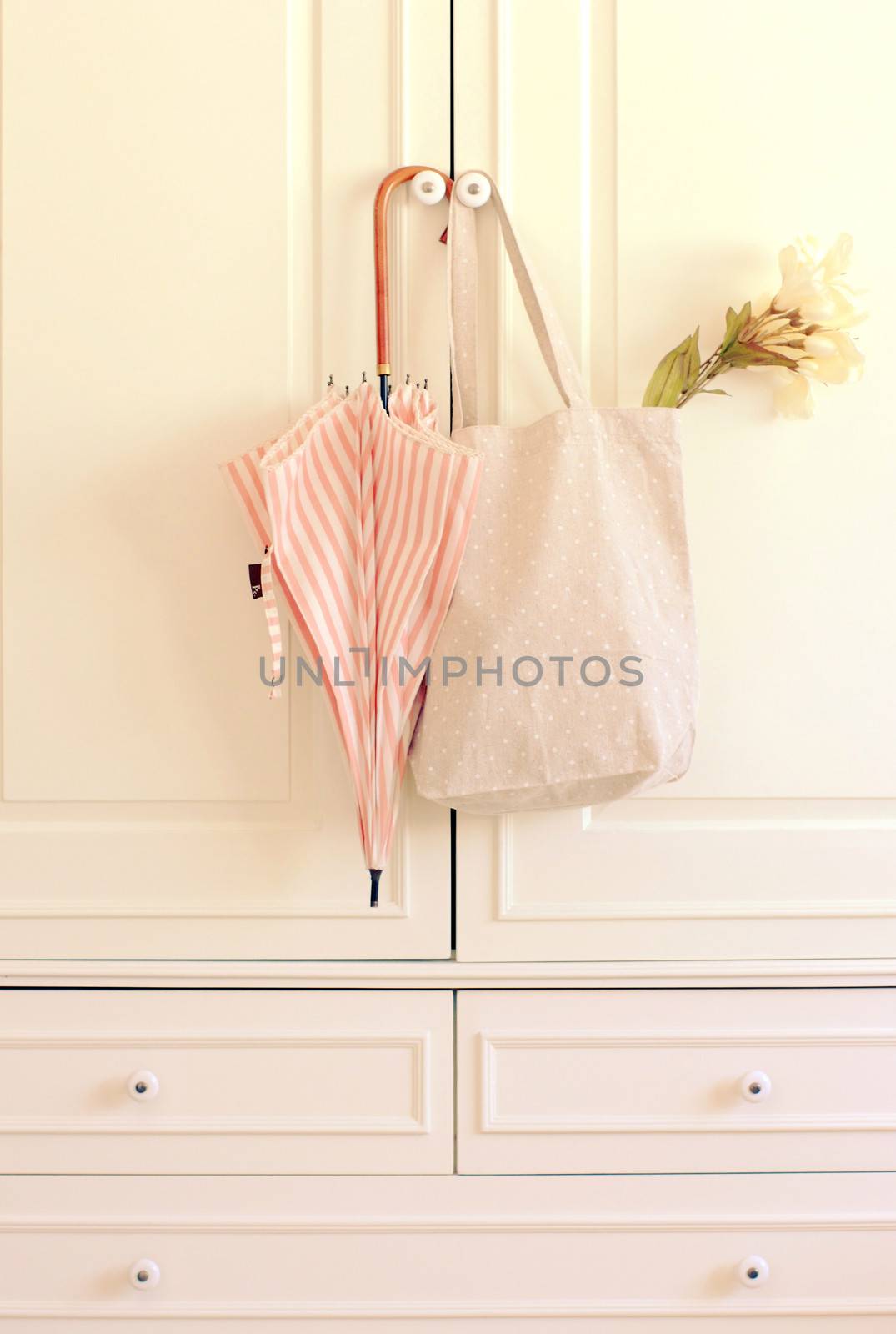 Umbrella and tote bag hanging on vintage wardrobe with retro filter effect