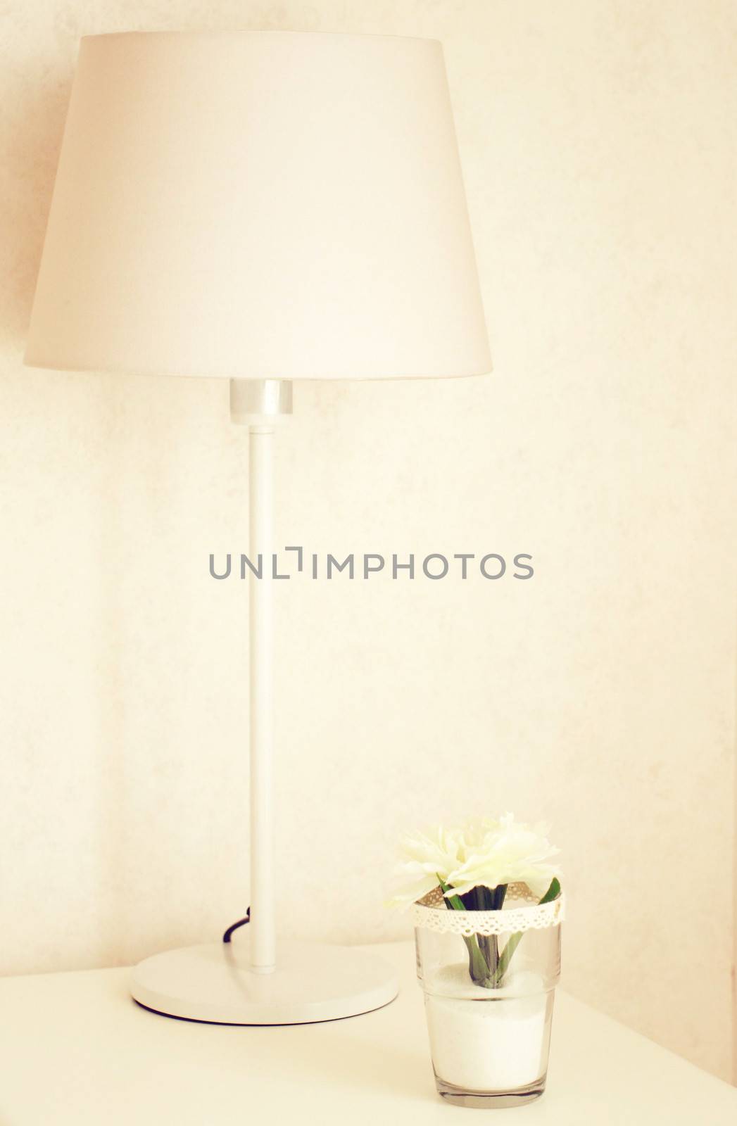Lamp and flower on the table near bed with retro filter effect  by nuchylee