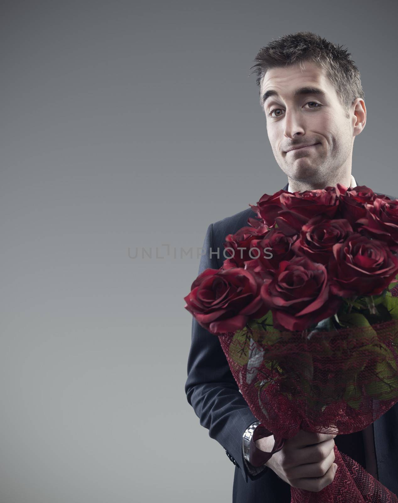 Man holding out large bouquet of red roses 