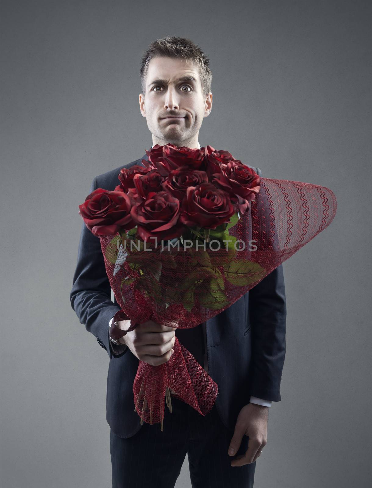 Shocked man holding out large bouquet of red roses 