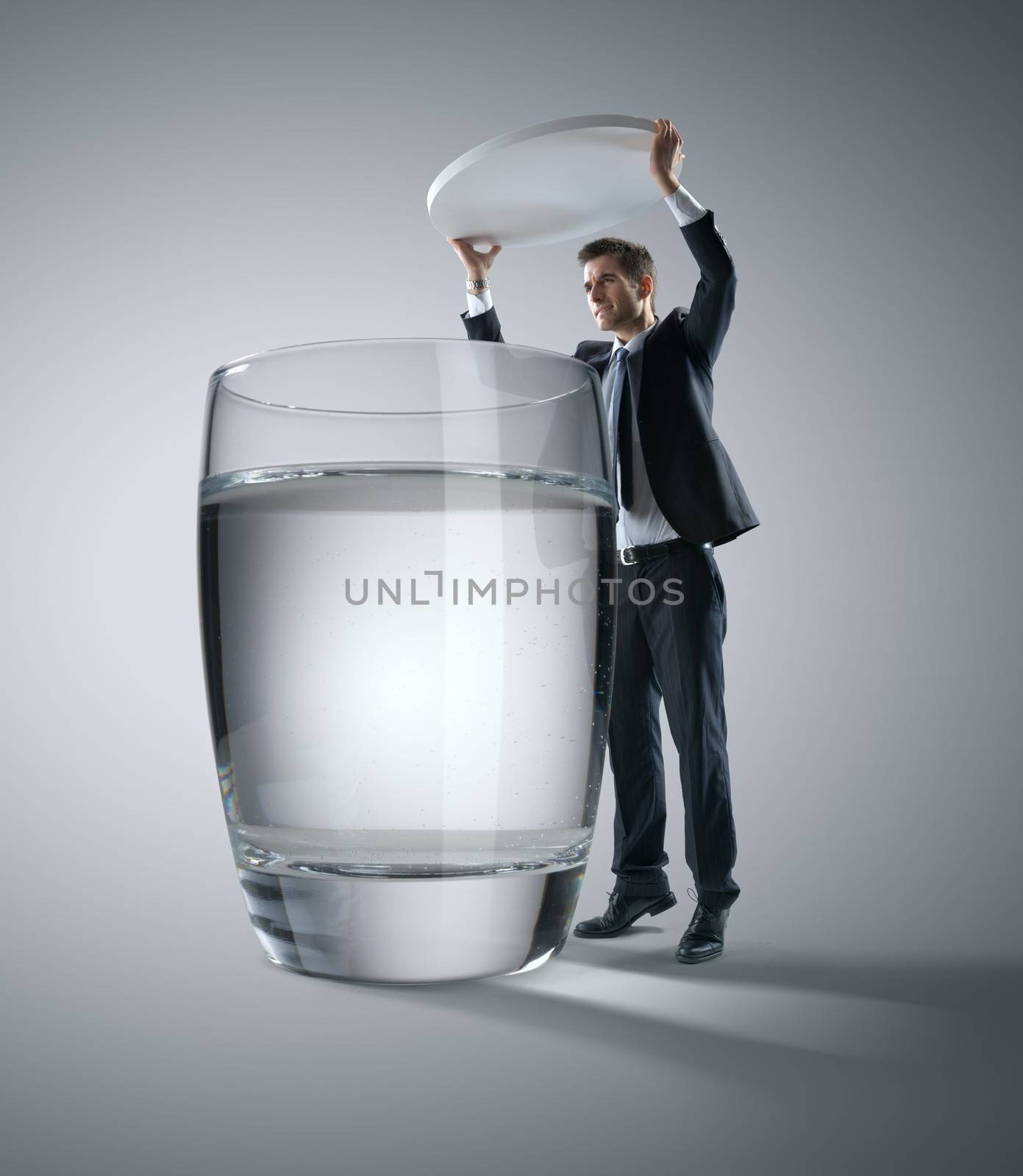 Businessman putting a huge pill into a glass of water.