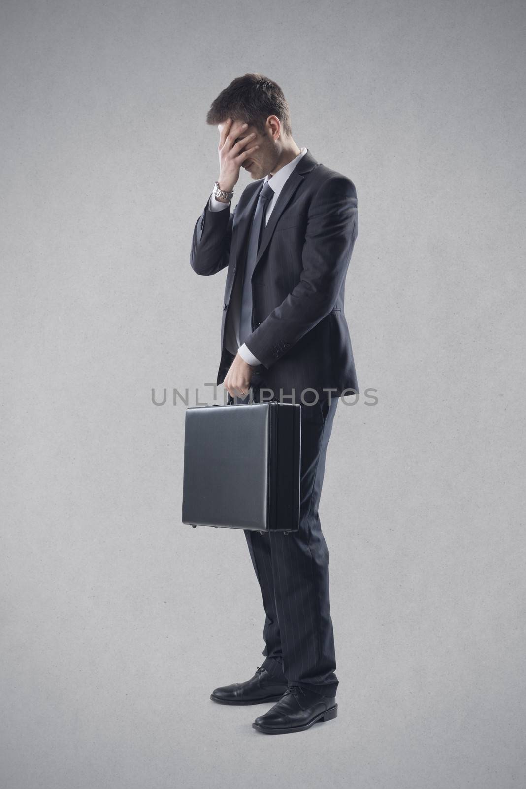 Frustrated young businessman covering his eyes.