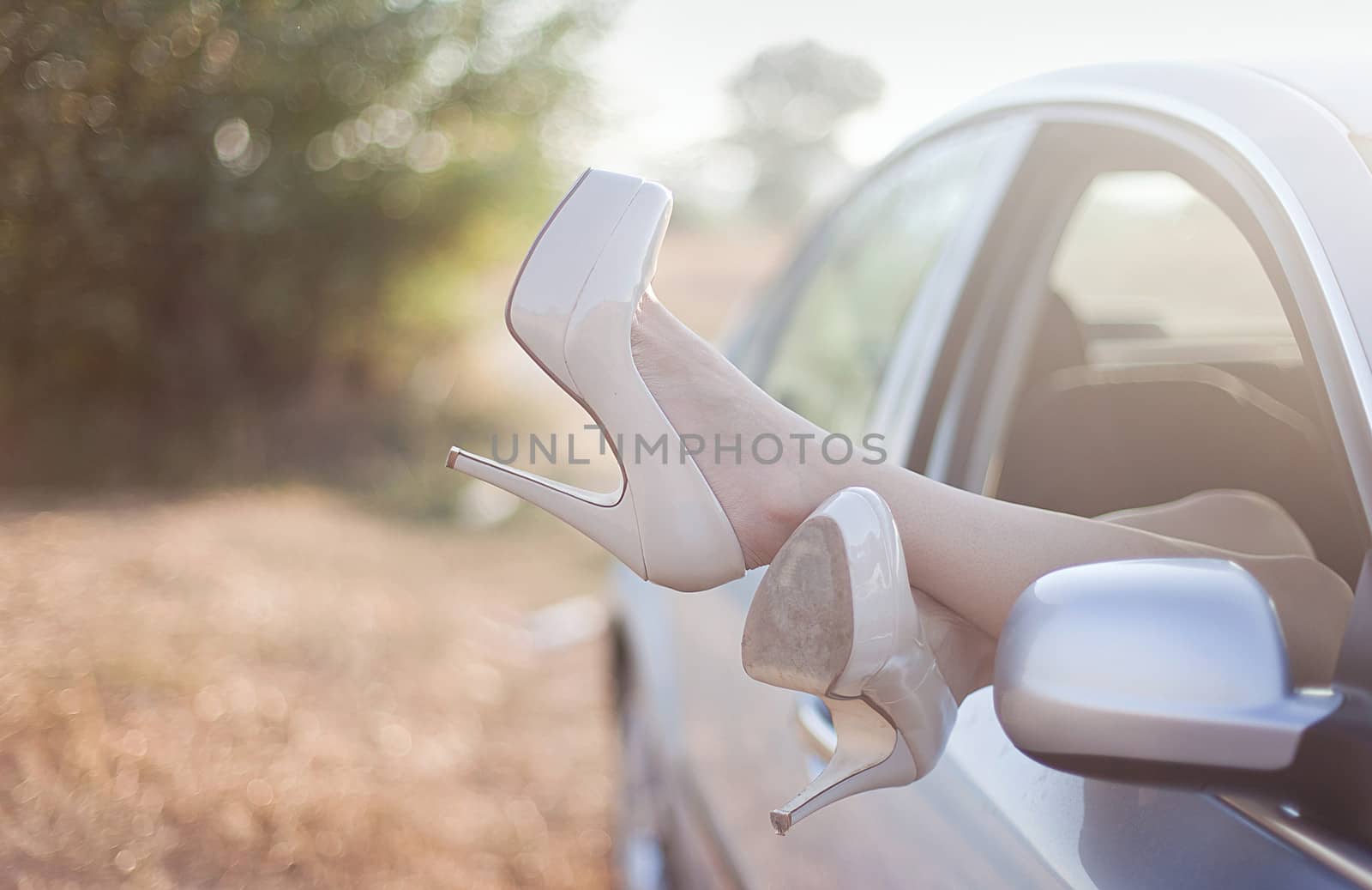 Sexy woman legs on high heels out the windows in car. by uros93