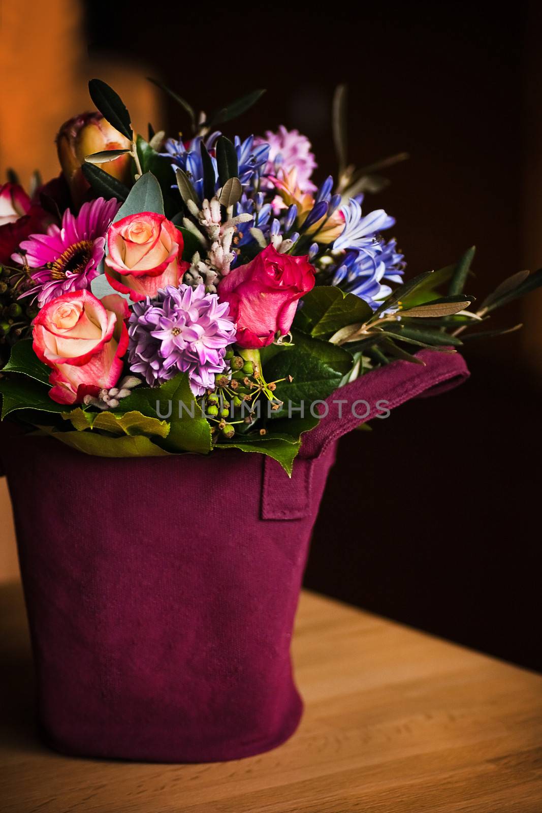Vase like a shopping bag filled with spring flowers and with dark background on a table