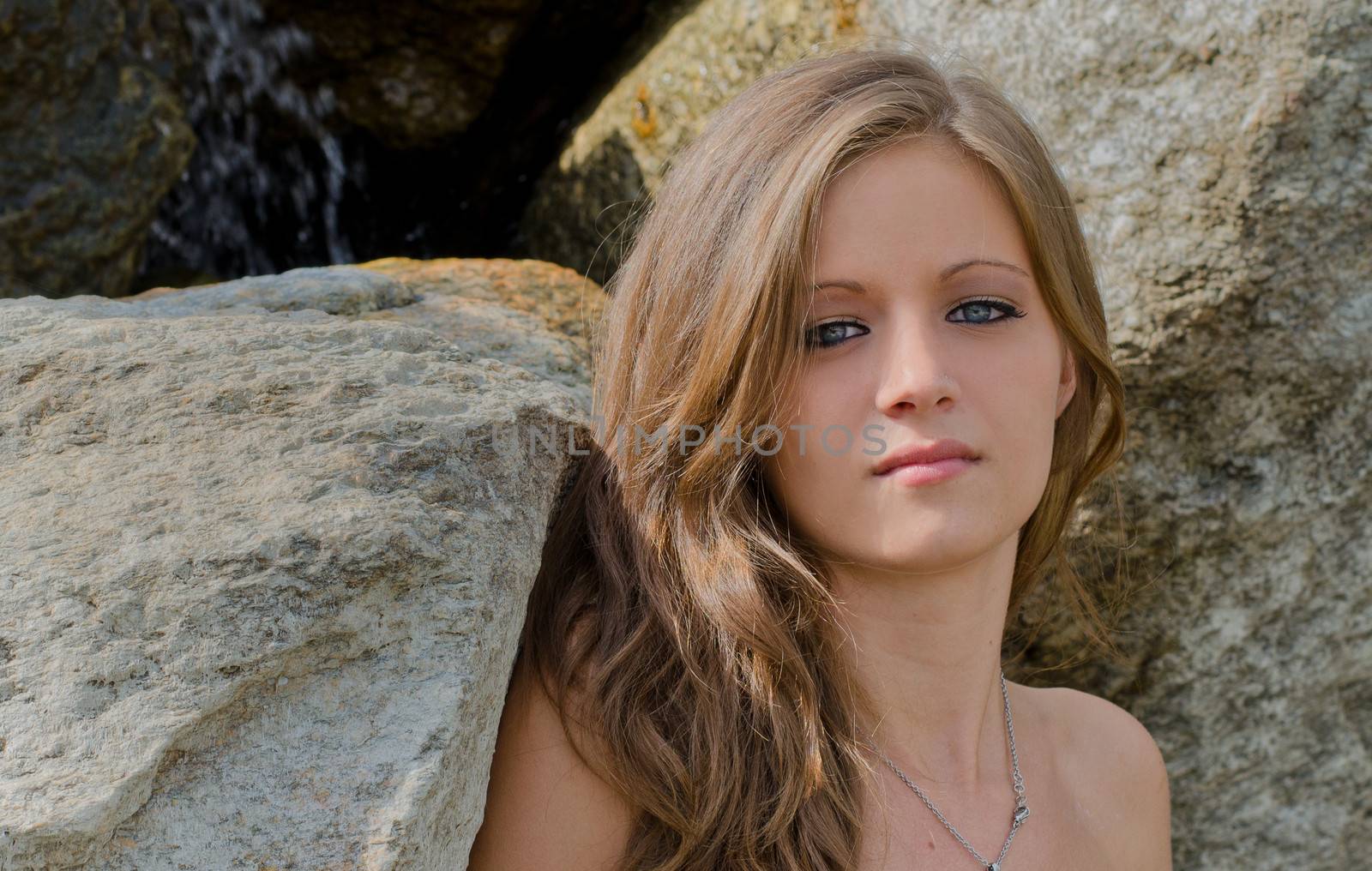 Headshot of pretty blue eyed, brunette girl against rocks