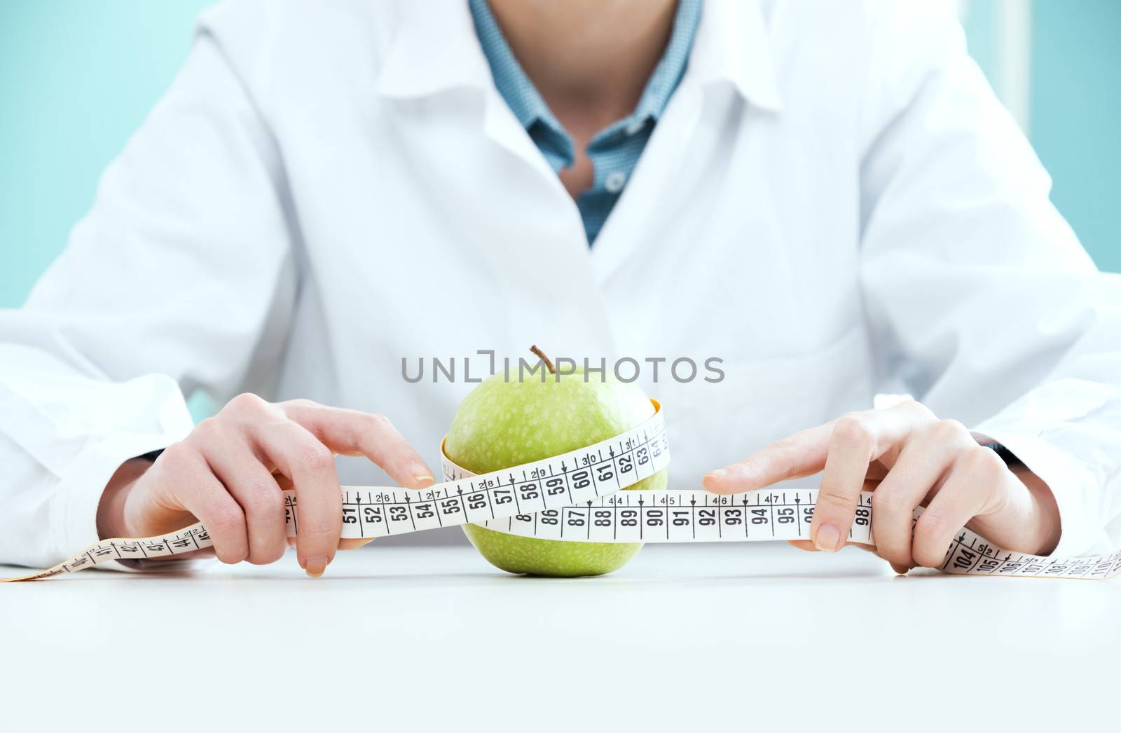 Young female doctor holding measuring tape and apple