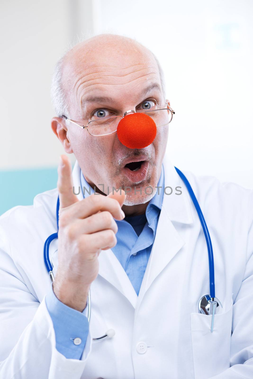 Funny senior doctor with red clown nose and funny expression.